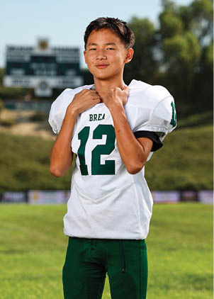 A young man wearing a white and black jersey with the number 14 on it. Description generated by AI