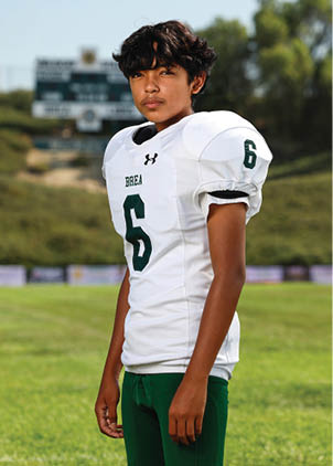 A young man wearing a white and black jersey with the number 14 on it. Description generated by AI