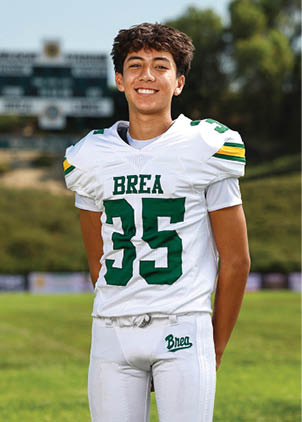 A young man wearing a white and black jersey with the number 14 on it. Description generated by AI