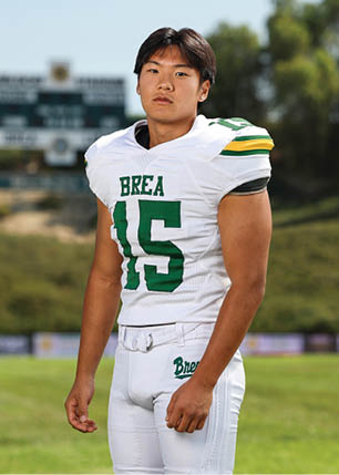 A young man wearing a white and black jersey with the number 14 on it. Description generated by AI