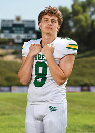 A young man wearing a white and black jersey with the number 14 on it. Description generated by AI