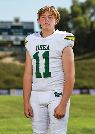 A young man wearing a white and black jersey with the number 14 on it. Description generated by AI