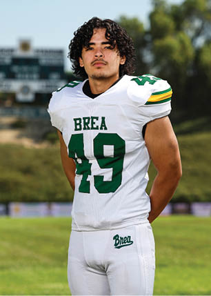 A young man wearing a white and black jersey with the number 14 on it. Description generated by AI