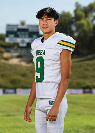 A young man wearing a white and black jersey with the number 14 on it. Description generated by AI