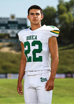 A young man wearing a white and black jersey with the number 14 on it. Description generated by AI