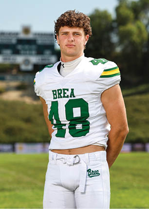 A young man wearing a white and black jersey with the number 14 on it. Description generated by AI
