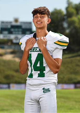 A young man wearing a white and black jersey with the number 14 on it. Description generated by AI
