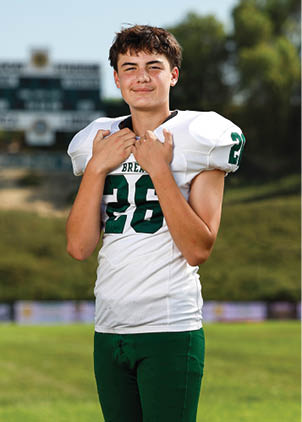 A young man wearing a white and black jersey with the number 14 on it. Description generated by AI