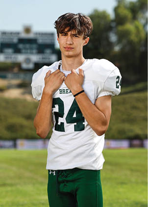 A young man wearing a white and black jersey with the number 14 on it. Description generated by AI