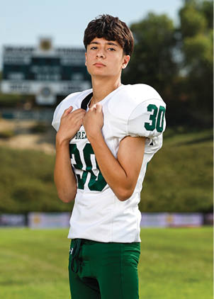 A young man wearing a white and black jersey with the number 14 on it. Description generated by AI