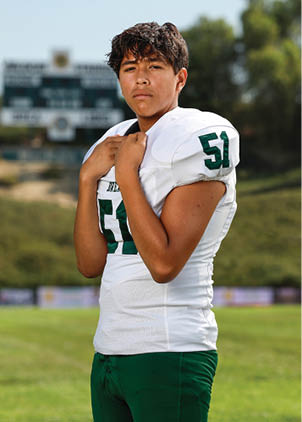 A young man wearing a white and black jersey with the number 14 on it. Description generated by AI