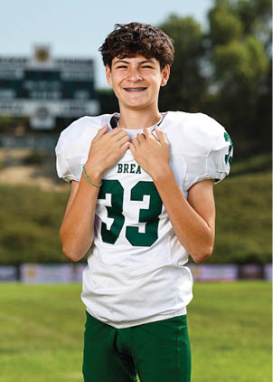 A young man wearing a white and black jersey with the number 14 on it. Description generated by AI