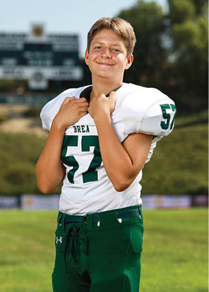 A young man wearing a white and black jersey with the number 14 on it. Description generated by AI