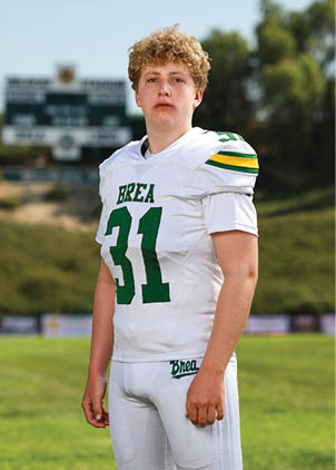 A young man wearing a white and black jersey with the number 14 on it. Description generated by AI