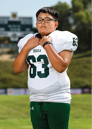 A young man wearing a white and black jersey with the number 14 on it. Description generated by AI