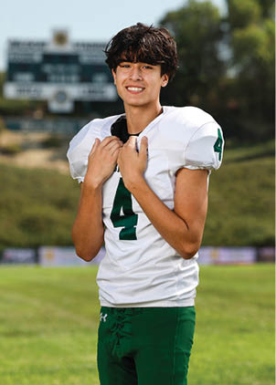 A young man wearing a white and black jersey with the number 14 on it. Description generated by AI