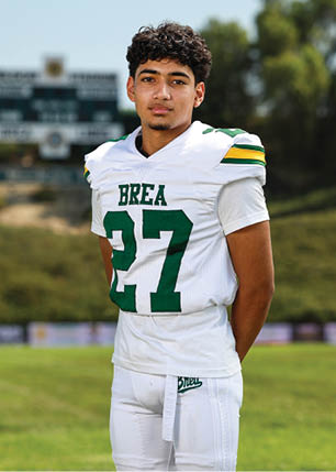 A young man wearing a white and black jersey with the number 14 on it. Description generated by AI