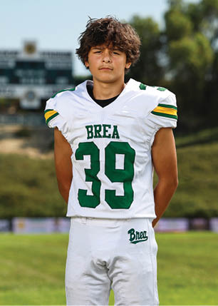 A young man wearing a white and black jersey with the number 14 on it. Description generated by AI