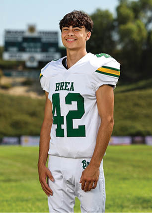 A young man wearing a white and black jersey with the number 14 on it. Description generated by AI