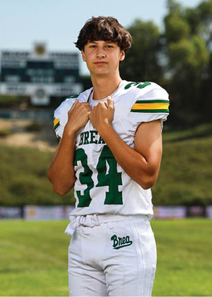 A young man wearing a white and black jersey with the number 14 on it. Description generated by AI