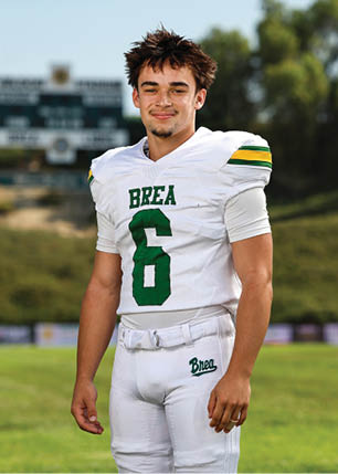 A young man wearing a white and black jersey with the number 14 on it. Description generated by AI