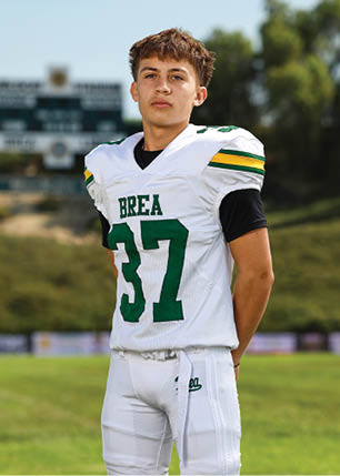 A young man wearing a white and black jersey with the number 14 on it. Description generated by AI