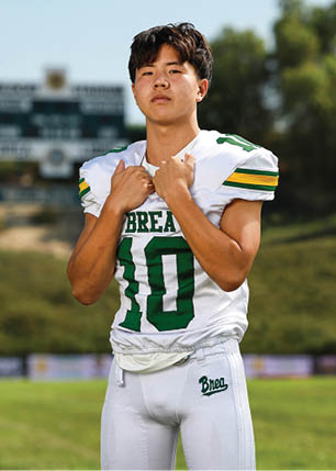 A young man wearing a white and black jersey with the number 14 on it. Description generated by AI