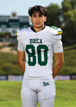 A young man wearing a white and black jersey with the number 14 on it. Description generated by AI