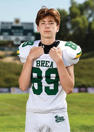 A young man wearing a white and black jersey with the number 14 on it. Description generated by AI
