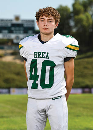 A young man wearing a white and black jersey with the number 14 on it. Description generated by AI