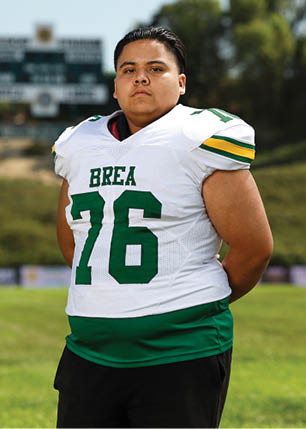 A young man wearing a white and black jersey with the number 14 on it. Description generated by AI