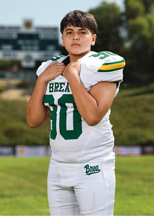 A young man wearing a white and black jersey with the number 14 on it. Description generated by AI