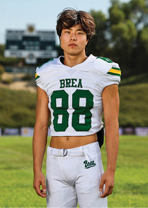 A young man wearing a white and black jersey with the number 14 on it. Description generated by AI