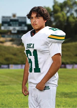 A young man wearing a white and black jersey with the number 14 on it. Description generated by AI