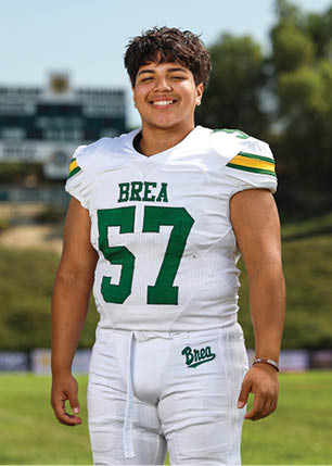 A young man wearing a white and black jersey with the number 14 on it. Description generated by AI