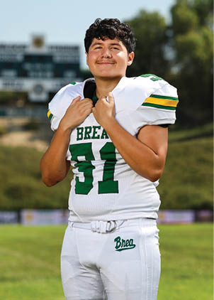 A young man wearing a white and black jersey with the number 14 on it. Description generated by AI