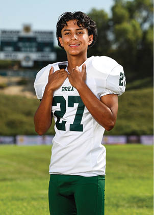 A young man wearing a white and black jersey with the number 14 on it. Description generated by AI