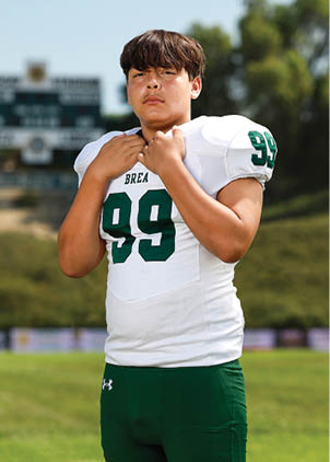 A young man wearing a white and black jersey with the number 14 on it. Description generated by AI