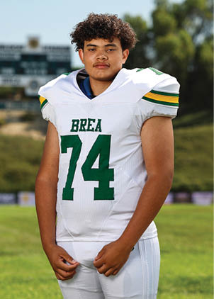 A young man wearing a white and black jersey with the number 14 on it. Description generated by AI