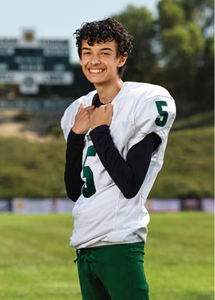 A young man wearing a white and black jersey with the number 14 on it. Description generated by AI