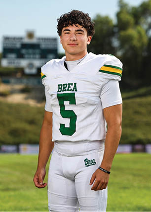 A young man wearing a white and black jersey with the number 14 on it. Description generated by AI