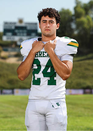 A young man wearing a white and black jersey with the number 14 on it. Description generated by AI