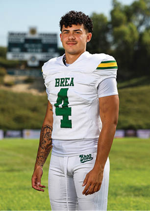 A young man wearing a white and black jersey with the number 14 on it. Description generated by AI