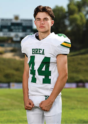 A young man wearing a white and black jersey with the number 14 on it. Description generated by AI