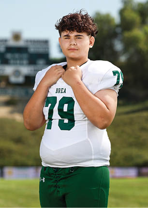A young man wearing a white and black jersey with the number 14 on it. Description generated by AI
