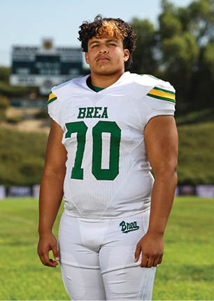 A young man wearing a white and black jersey with the number 14 on it. Description generated by AI