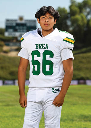 A young man wearing a white and black jersey with the number 14 on it. Description generated by AI