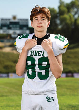 A young man wearing a white and black jersey with the number 14 on it. Description generated by AI