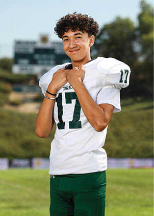 A young man wearing a white and black jersey with the number 14 on it. Description generated by AI