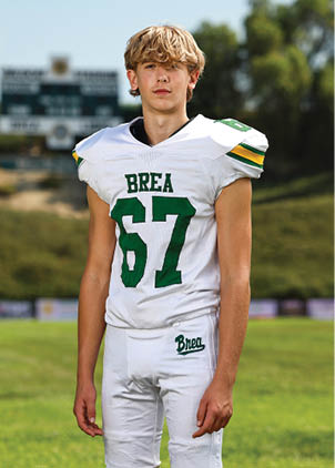 A young man wearing a white and black jersey with the number 14 on it. Description generated by AI